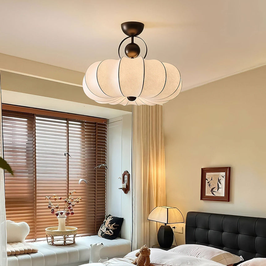 Pleated silk ceiling light lit in a bedroom with wood blinds and a black sofa
