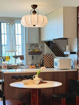 Pleated silk ceiling light in a kitchen above a round table with a checked floor