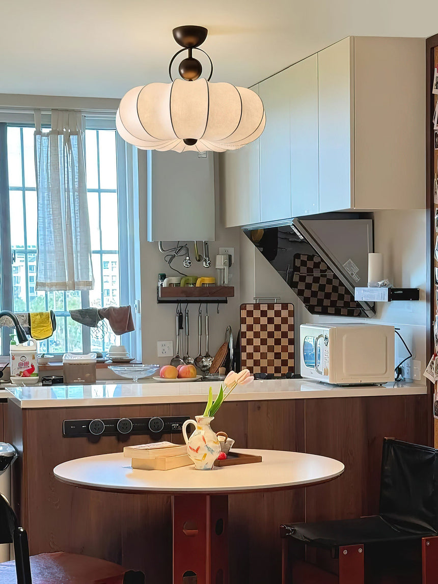 Pleated silk ceiling light in a kitchen above a round table with a checked floor