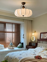 Pleated silk ceiling light in a bedroom with a round wall light and wood blinds