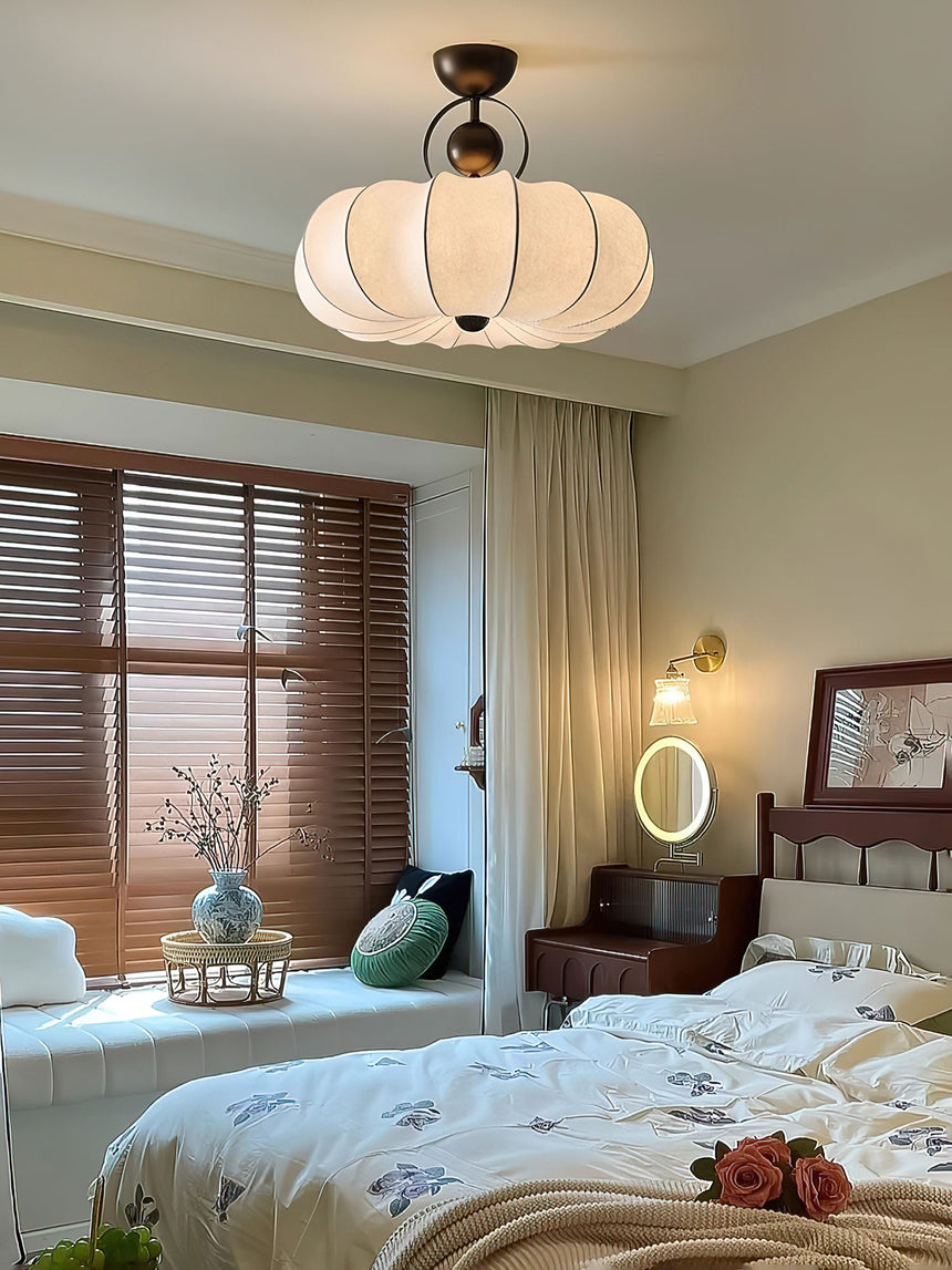 Pleated silk ceiling light in a bedroom with a round wall light and wood blinds