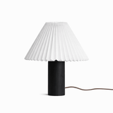 Pleated white shade on a black wood base against a plain white ground