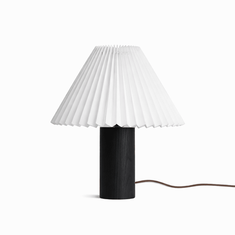 Pleated white shade on a black wood base against a plain white ground