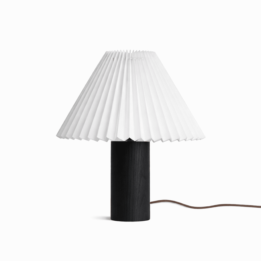 Pleated white shade on a black wood base against a plain white ground