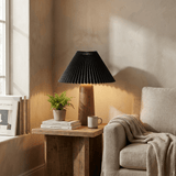 Pleated black shade lamp lit on a side table in a bright living room