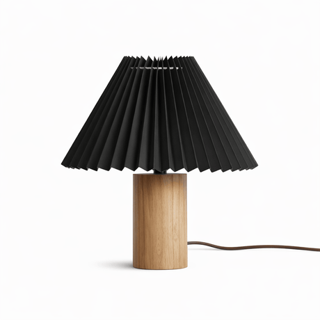 Pleated black shade on a pale wood cylinder base against a white ground