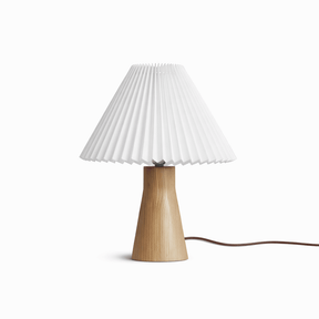 Pleated white shade on a short pale wood base seen against a white ground