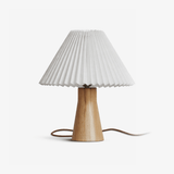 Pleated table lamp with a white shade on a pale wood base, plain ground