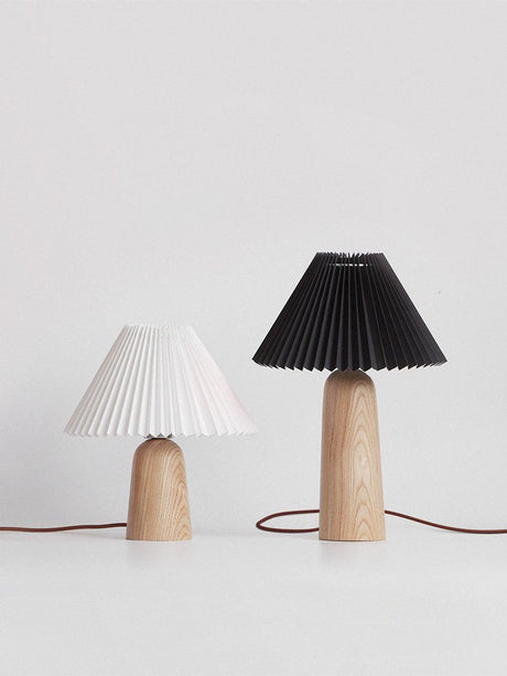 A white shaded lamp and a black shaded lamp side by side on a white ground