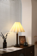 Pleated table lamp seen from a distance on a console by a window