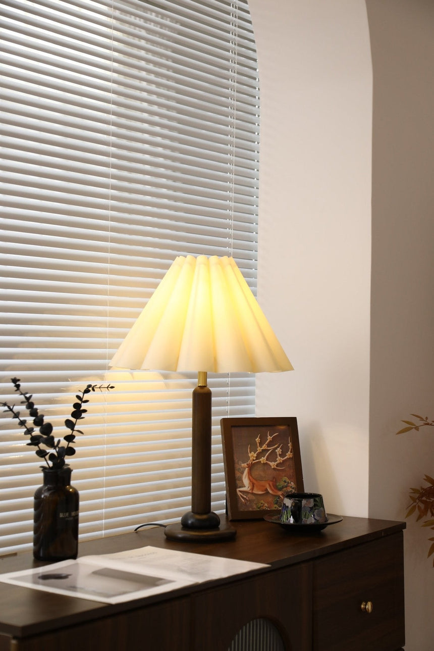 Pleated table lamp seen from a distance on a console by a window