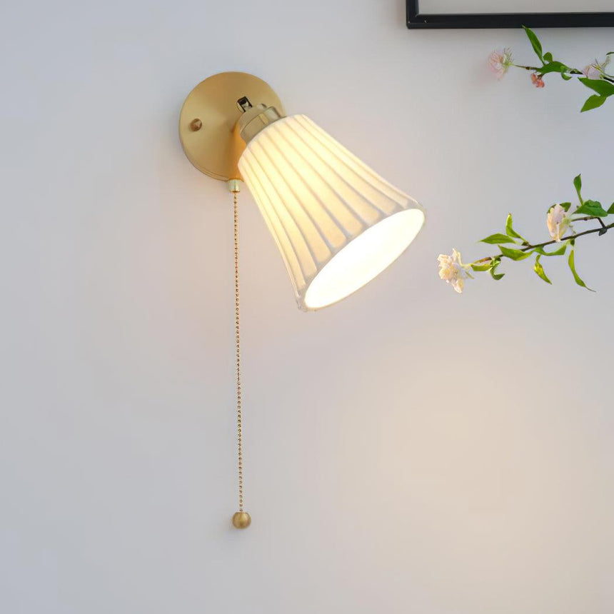 The shade tilted toward the wall, lit warm beside a flowering branch