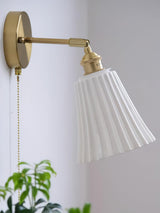 Close view of the pleated shade on its brass joint with the pull chain
