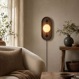 Lamp lit above a console beside a pale armchair and a drawn curtain