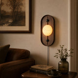 Lamp lit above a leather sofa beside a framed print and a low table