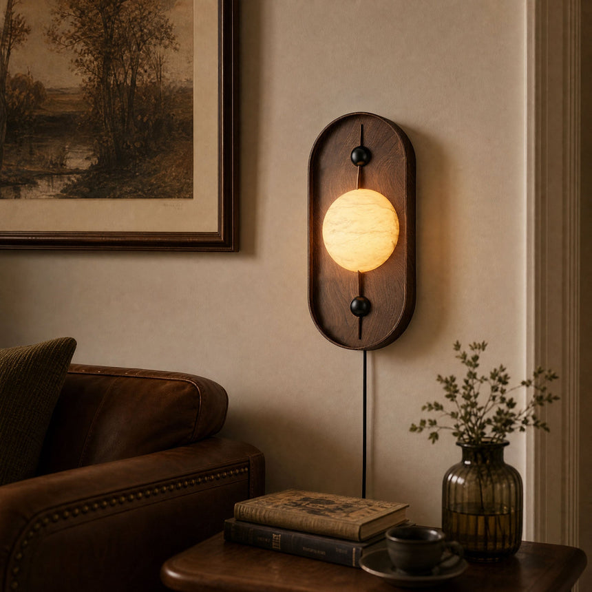 Lamp lit above a leather sofa beside a framed print and a low table