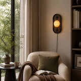 Lamp lit beside a bookcase above an armchair with a folded throw