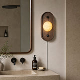 Lamp lit beside a bathroom mirror above a basin with a soap bottle