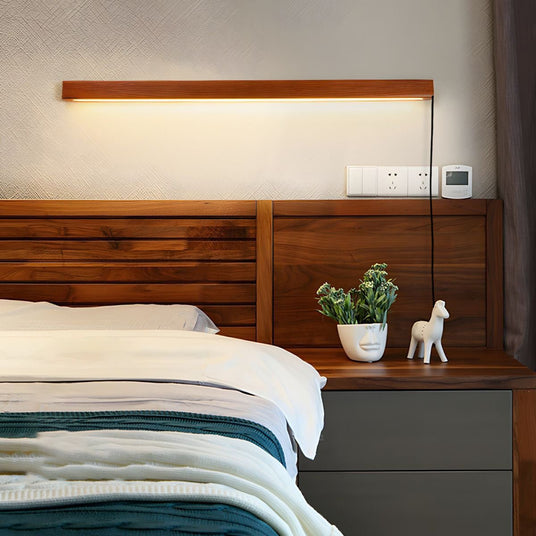 Walnut bar lit above a wood headboard beside a nightstand