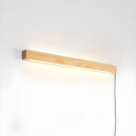 The short pine bar lit on a plain wall with its cord hanging down