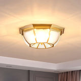 Octagonal brass ceiling light lit against a white ceiling