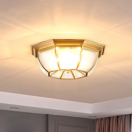 Octagonal brass ceiling light lit against a white ceiling