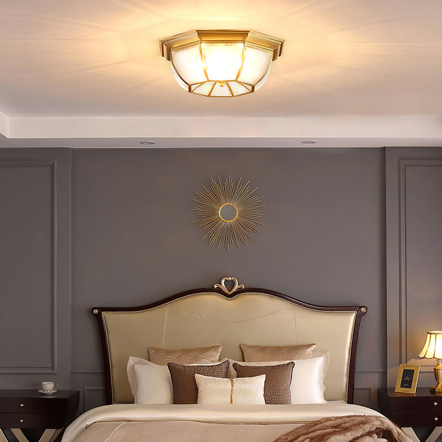 Octagonal brass ceiling light above a bed with a curved headboard