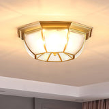 Octagonal brass ceiling light lit close against the plaster