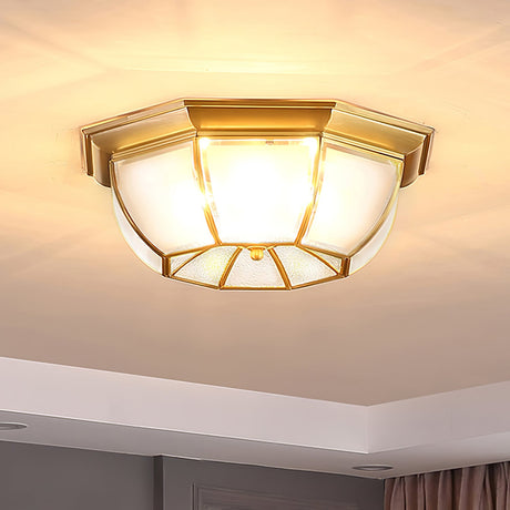 Octagonal brass ceiling light lit close against the plaster