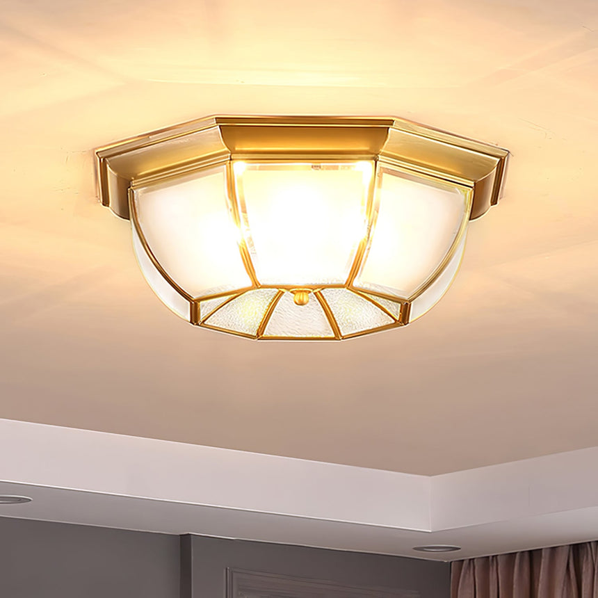 Octagonal brass ceiling light lit close against the plaster
