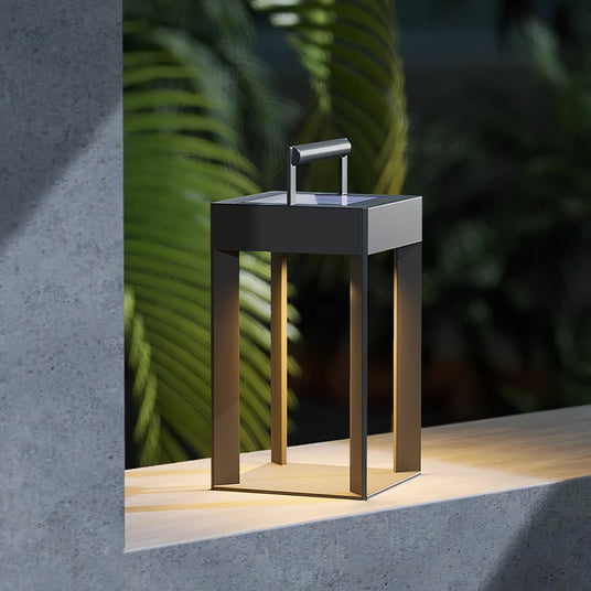 The lantern lit on a concrete garden ledge with ferns and bamboo behind