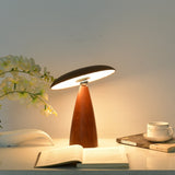 Portable table lamp lit warm on a desk beside a cup