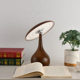 Portable table lamp lit over an open book and a plant