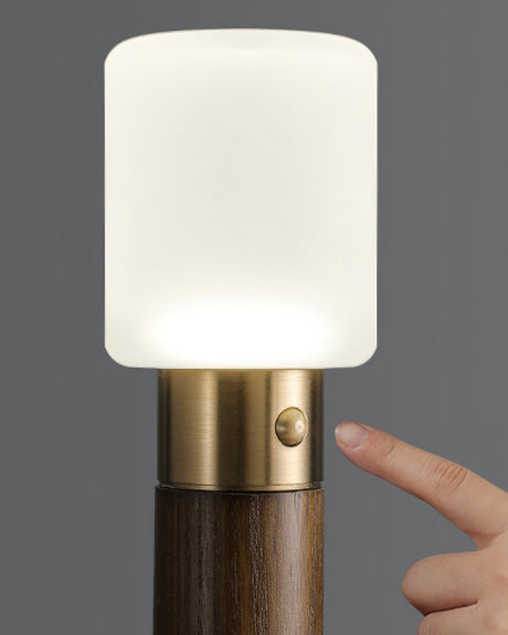 A finger pressing the small button on the brass collar of the lit lamp