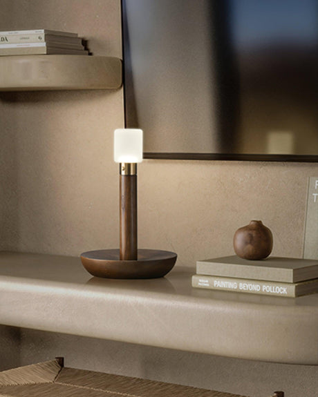 Portable table lamp lit on a plaster ledge beside two stacked books