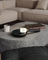 Portable table lamp lit on a stone coffee table beside a cup and a tray