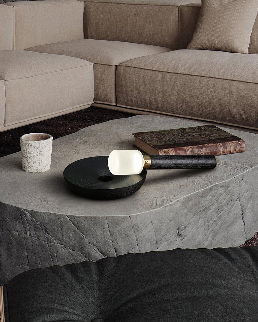 Portable table lamp lit on a stone coffee table beside a cup and a tray