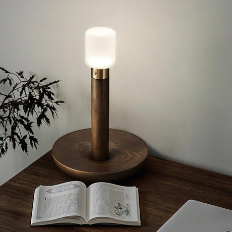 Portable table lamp lit in a corner above an open book on the floor