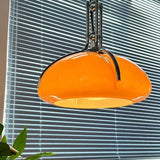 The orange shade lit beside a blue window blind in a bright room