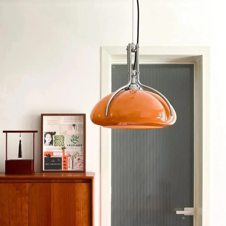 The orange shade lit above a wooden sideboard with framed pictures
