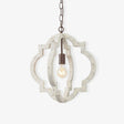 A quatrefoil frame of aged white wood around a single filament lamp on a chain