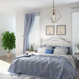 Hung in a bedroom above a bed with blue bedding, curtains and framed prints