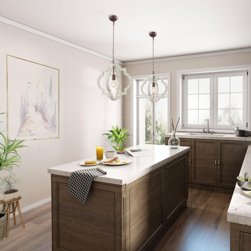 Two of them lit above a dark kitchen island with stools and a window behind