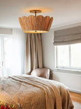 Raffia ceiling light above a bed with a woven blind and a tall curtain