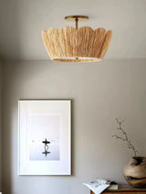 Raffia ceiling light lit near a framed print and a ceramic vase on a shelf