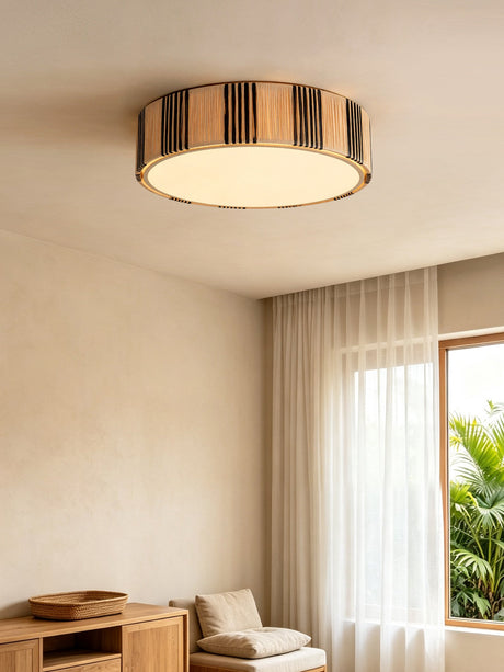 Striped raffia drum ceiling light in a room with a wood cabinet and open curtains