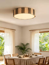 Striped raffia drum ceiling light above a dining table set with pottery