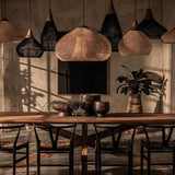 Several of the woven shades hung over a long dining table with chairs and a window