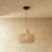 A natural rattan lantern shade, openly woven, glowing from the lamp inside it
