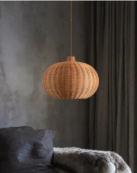 Round woven shade lit against a dark gray wall